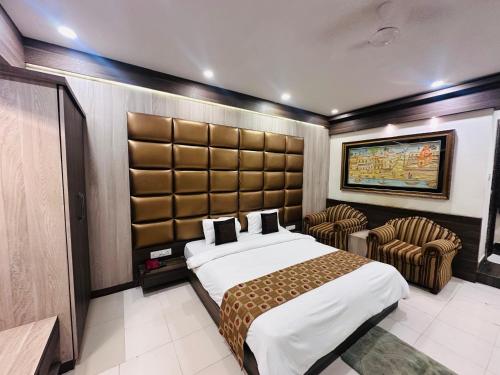 a bedroom with a large bed and two chairs at Hotel OK International in Varanasi
