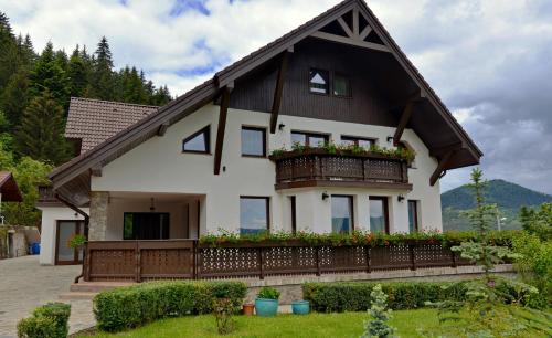 a house with a balcony with flowers on it at Pensiunea Drumul Plutasilor in Alexandru cel Bun