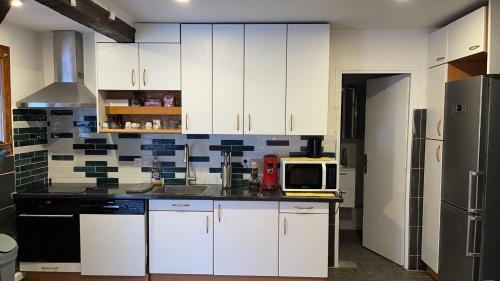 une cuisine avec des armoires blanches et un micro-ondes dans l'établissement Havre de paix proche Paris et La Défense, à Bezons