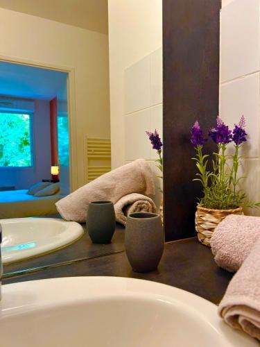 une salle de bain avec une baignoire et un lavabo avec des fleurs violettes dans l'établissement Joli T2 niché dans les arbres au cœur du bassin, à Audenge