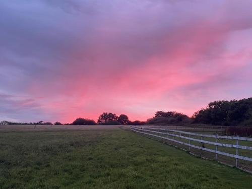 a field with a fence and a red sky at Rose Lodge - Uk40019 in Halwill