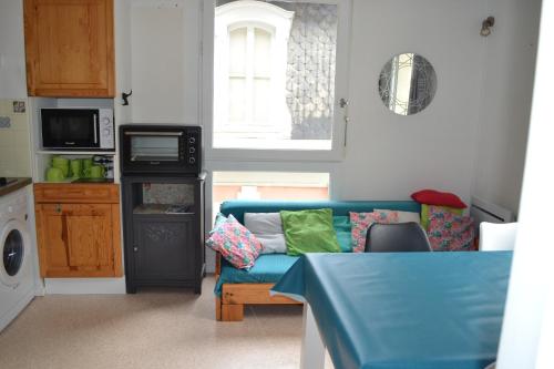 un salon avec un canapé bleu dans une cuisine dans l'établissement Plein centre - Idéal Familles 3 enfants, à Cauterets