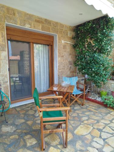 a patio with a table and chairs and a window at THANground floor in Nea Kalikratia