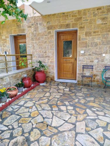 a stone house with a wooden door and a patio at THANground floor in Nea Kalikratia