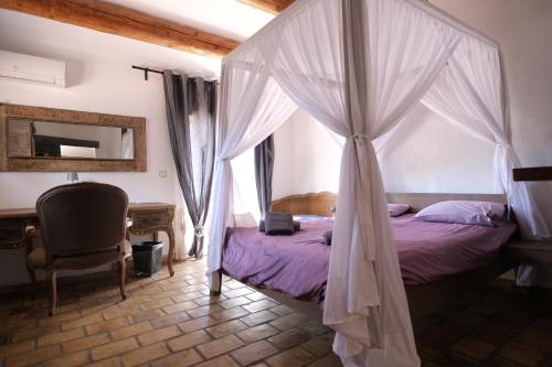 a bedroom with a canopy bed and a desk at magnificent detached villa with heated swimming pool and jacuzzi, in aureille, in the alpilles – 8 people in Aureille
