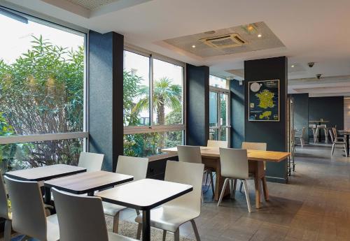 une salle à manger avec tables, chaises et fenêtres dans l'établissement B&B HOTEL Marseille Prado Parc des Expositions, à Marseille