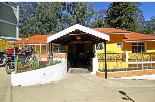 a yellow house with a gate and a driveway at Happy Valley in Kodaikānāl
