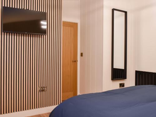 a bedroom with a bed and a television on a wall at Willow Lodge in Ingleton 