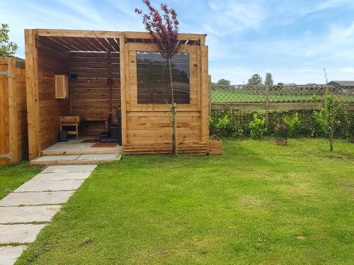 a wooden shed in a yard with a lawn at Algwen Cabin in West Walton