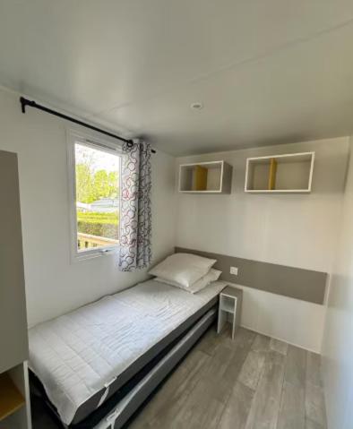 un petit lit dans une chambre avec une fenêtre dans l'établissement Bungalow, 3 chambres, à La Bernerie-en-Retz