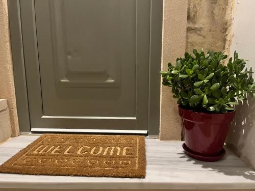a welcome mat in front of a door with a potted plant at Nymfea Ano Syros in Ano Syros