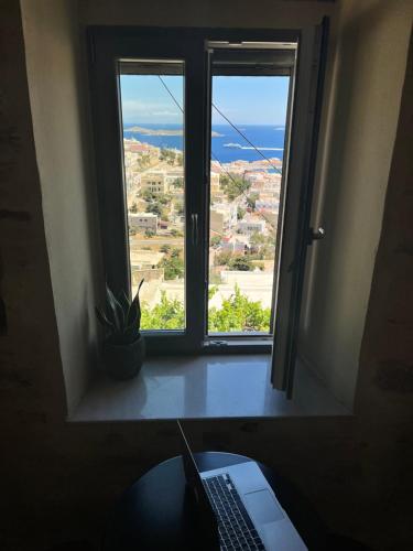 a window in a room with a laptop on a desk at Nymfea Ano Syros in Ano Syros