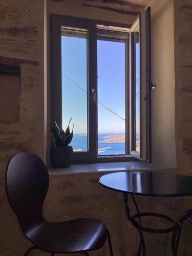 a table and a chair in a room with a window at Nymfea Ano Syros in Ano Syros