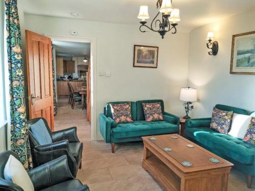 a living room with two green couches and a coffee table at Acacia Cottage in Wirksworth