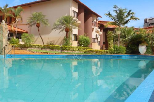 ein Swimmingpool vor einem Haus mit Palmen in der Unterkunft Recanto das Águas Quentes - TURISMO in Rio Quente