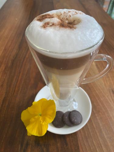a cup of coffee with a flower on a table at Falubíró Vendégháza in Bekölce