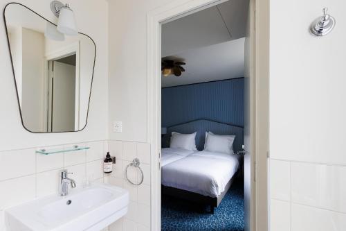 une salle de bain avec un lit, un lavabo et un miroir dans l'établissement Hôtel de Charonne, à Paris