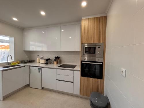 a kitchen with white cabinets and stainless steel appliances at Charming Baixa IV - 3 Room APT in Lavradio