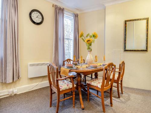 a dining room with a table and chairs and a clock at The Flat in Whitchurch