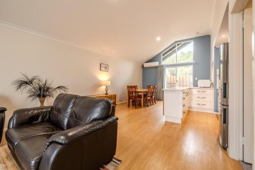 a living room with a leather couch and a kitchen at Albany Bayside by the BnB Collection in Albany