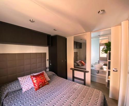 a bedroom with a bed and a bathroom with a sink at Camping Torre di Barisardo in Bari Sardo