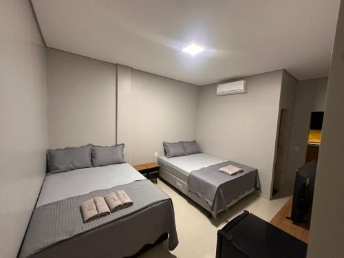 a bedroom with two beds and a tv in it at Hotel Araguaia Exclusive in Aruanã