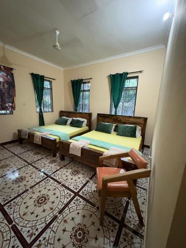 a bedroom with two beds and a table and windows at ZanziBalkan House Nungwi in Nungwi