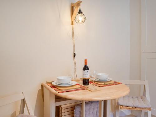 a table with a bottle of wine and two cups at Morwood Cottage in Porthcawl