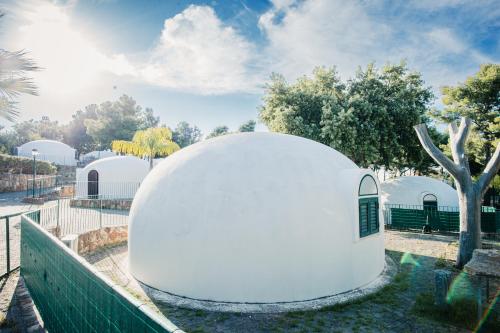 a white dome building in a park with a tree at Camping & Village Rais Gerbi in Pollina
