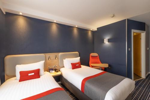 a hotel room with two beds and a chair at Holiday Inn Express London Croydon by IHG in Croydon
