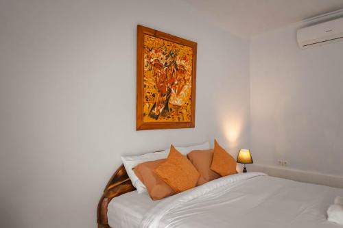 a bedroom with a bed with a painting on the wall at Mesari Cottage Guest House in Buleleng