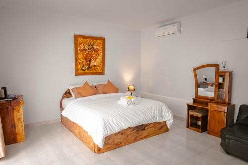 a bedroom with a bed with white sheets and a mirror at Mesari Cottage Guest House in Buleleng