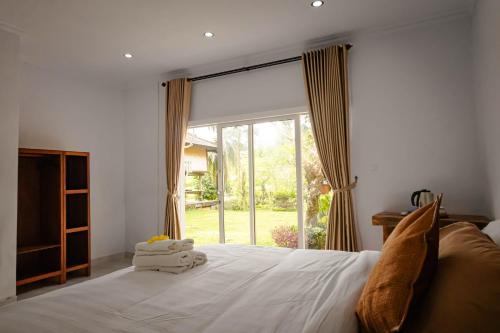 a bedroom with a bed with a large window at Mesari Cottage Guest House in Buleleng