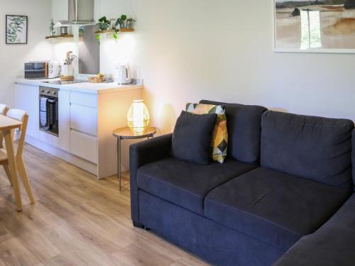 a living room with a blue couch and a kitchen at Gwynant Lodge - Uk47608 in Caernarfon