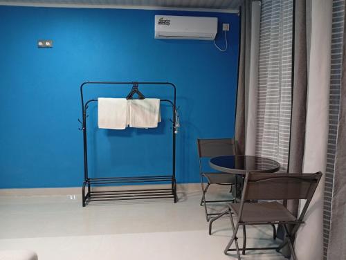 a room with a blue wall and a table and chairs at iruka guesthouse in Bandara