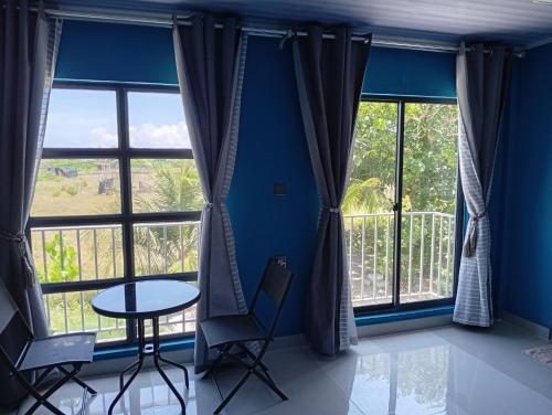 a room with blue walls and windows with a table and chairs at iruka guesthouse in Bandara