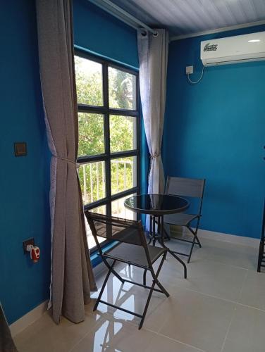 a table and chairs in a room with a window at iruka guesthouse in Bandara