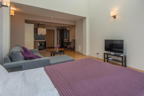 a bedroom with a bed and a couch and a tv at Parnidžio Kopa in Nida