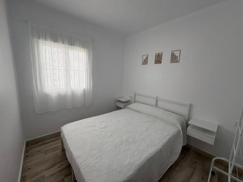 a white bedroom with a bed and a window at Casa Nova de Bolonia in Bolonia