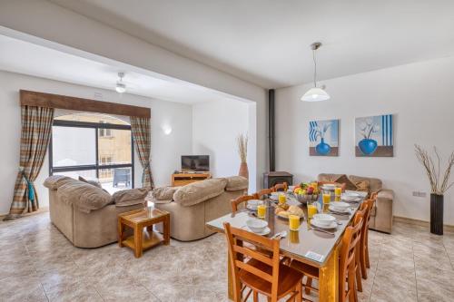 a living room with a table and chairs and a couch at Hgieri Holiday Home in Għasri
