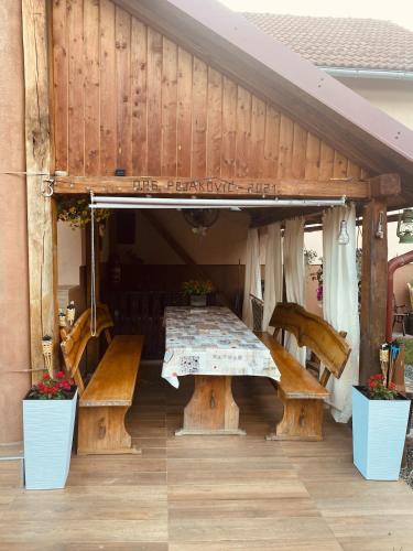 a patio with a table and benches under a roof at Ruralna kuća Pejaković in Stankovac
