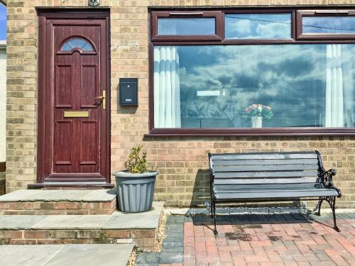 un banc devant une maison avec une porte dans l'établissement Covina - Uk43994, à Anderby
