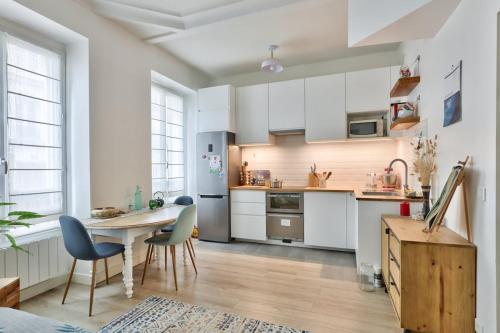 une cuisine avec des armoires blanches et une table et des chaises dans l'établissement Cosy et charmant appart 4 pers, à Paris