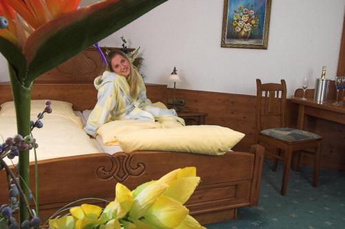 a woman sitting on a bed with an umbrella at Gasthof Mühle – Natur- & Wanderhotel in Rinchnach