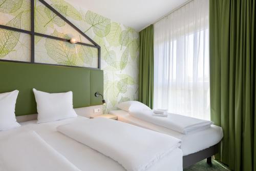 two beds in a room with green walls and a window at Mercure Hotel Hannover Mitte in Hannover