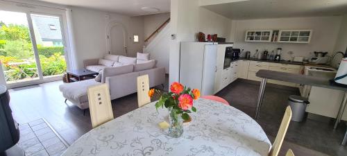 - une cuisine et un salon avec une table fleurie dans l'établissement maison bord de mer, à Plérin