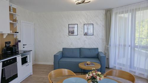 Una sala de estar con un sofá azul y una mesa. en Byala Cliff Sea View Suite, en Byala