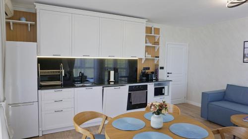 cocina con armarios blancos, mesa y sofá azul en Byala Cliff Sea View Suite, en Byala