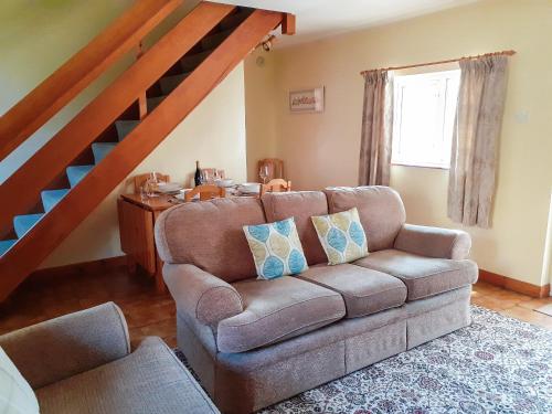 a living room with a couch and a staircase at Beck Cottage in Ennerdale Bridge