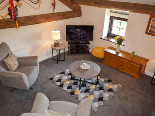 un salon avec un canapé et une télévision dans l'établissement The Studio At Malt Kiln Cottage, à Grizebeck